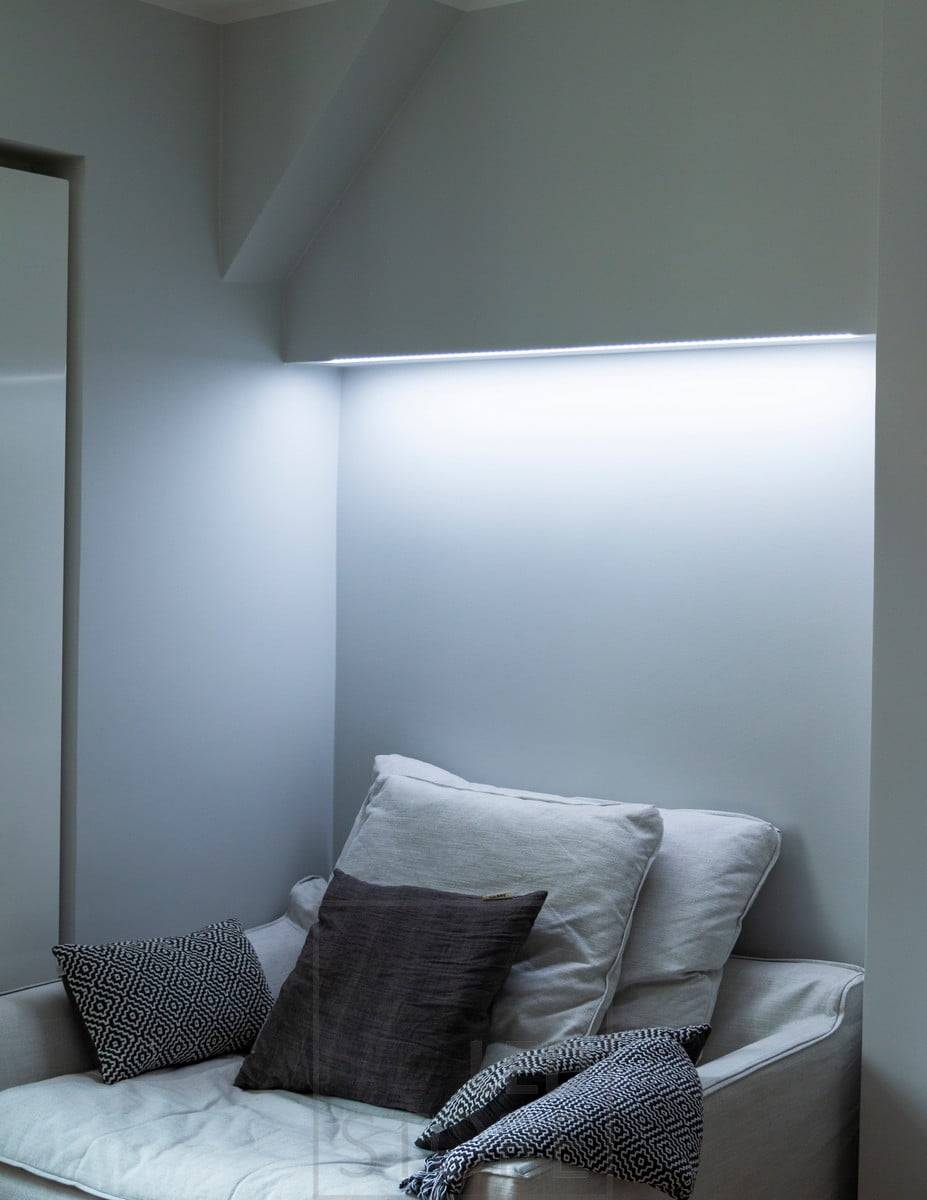 Bonita iluminación ambiental encima de la cama en el dormitorio. La tira de LED regulable en temperatura de color le permite ajustar la luz según su estado de ánimo y sus necesidades.